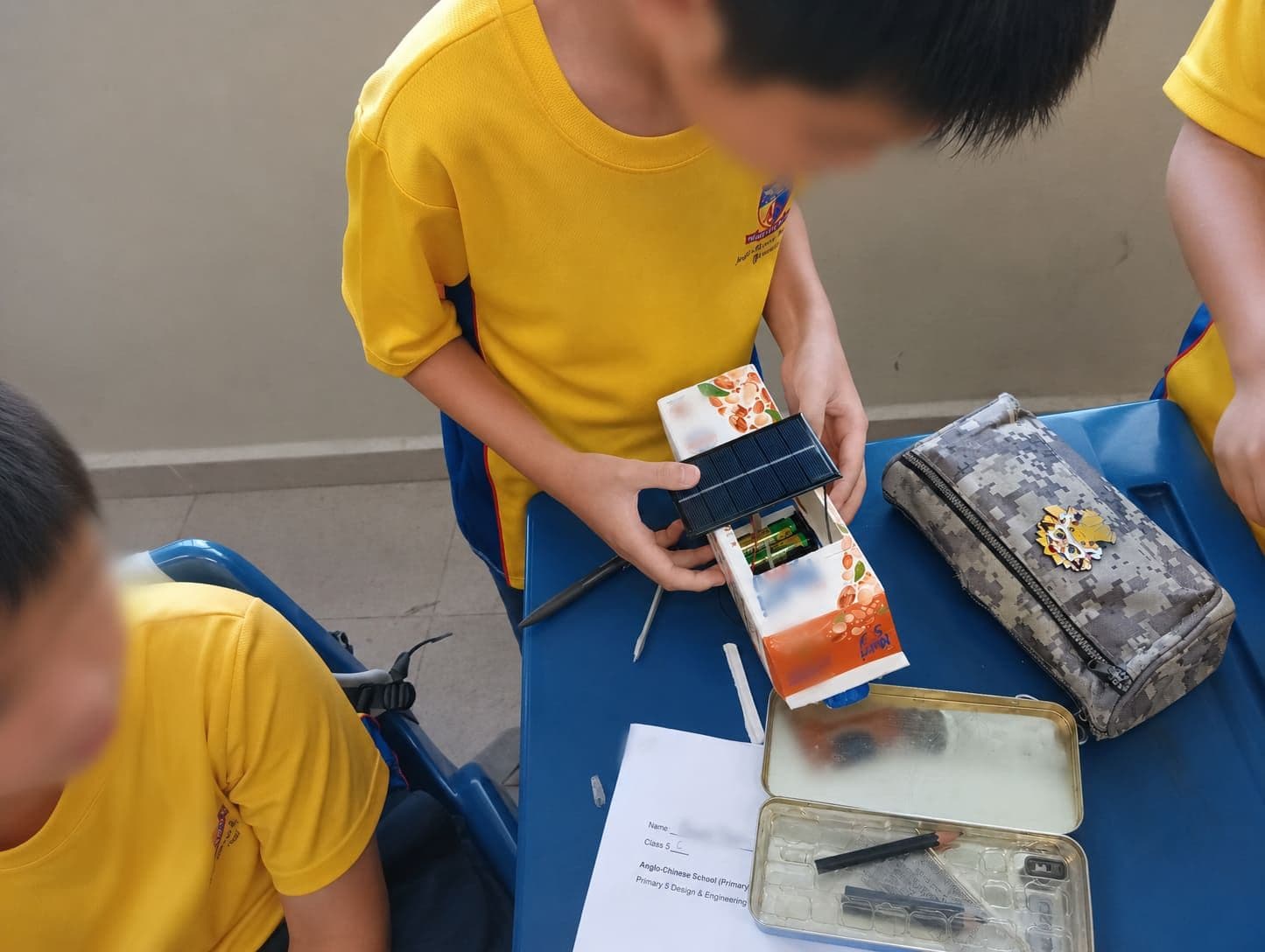 A student fitting a solar panel to a bus built from an upcycled juice carton