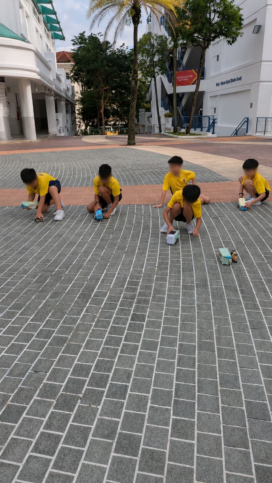Students crouched on a school forecourt releasing their self-built solar buses for a race