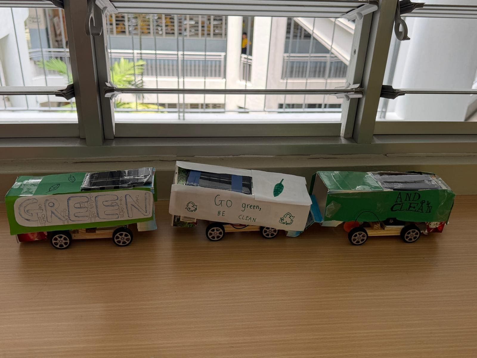 Three finished student solar buses lined up, decorated with sustainability slogans