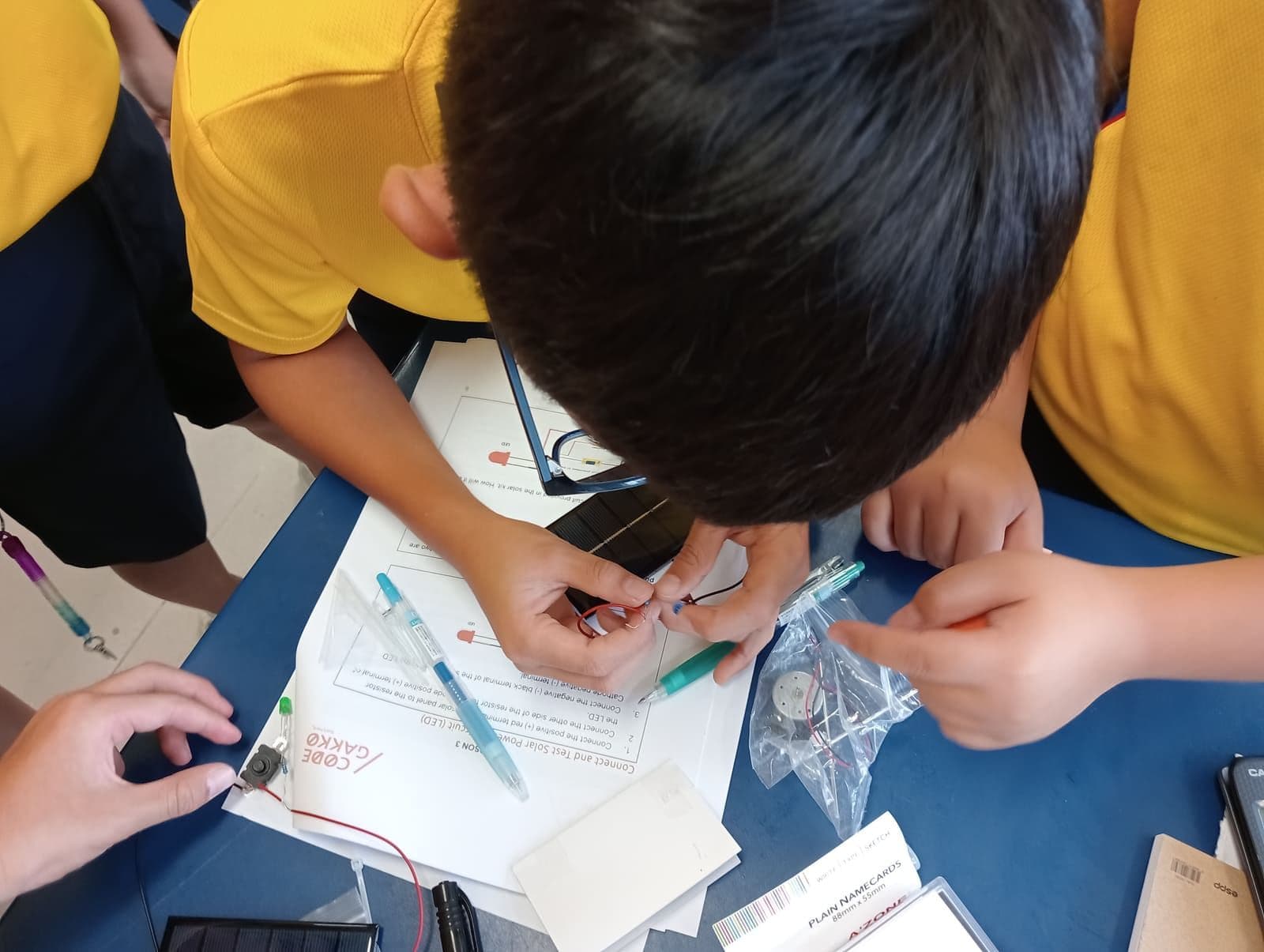 Students wiring an LED to a solar panel, following a Code Gakko worksheet
