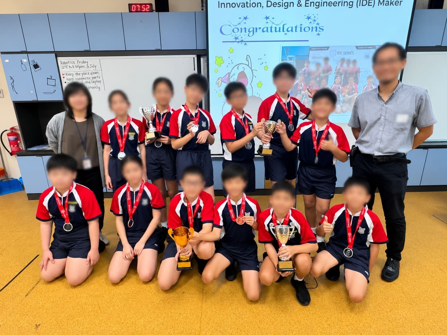 A primary school robotics team holding trophies and medals after an IDE Maker final