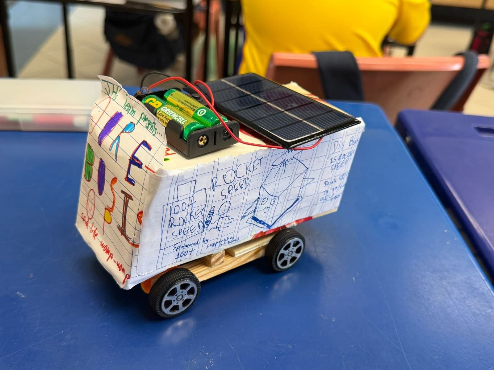 A solar-powered bus built by primary school students from a wooden chassis, decorated with hand-drawn artwork