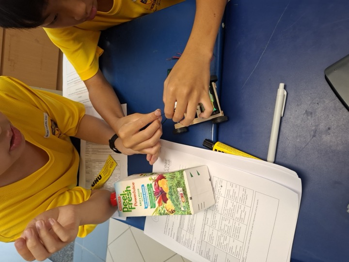 A student building a Solar Bus from a recycled juice carton.